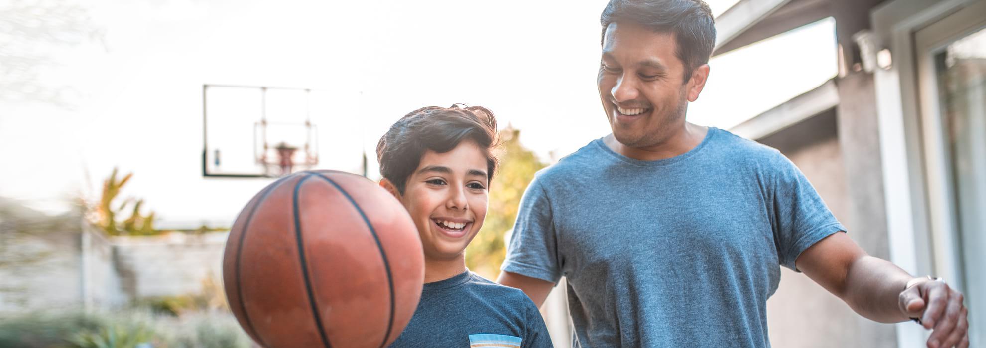 Father playing basketball with son.