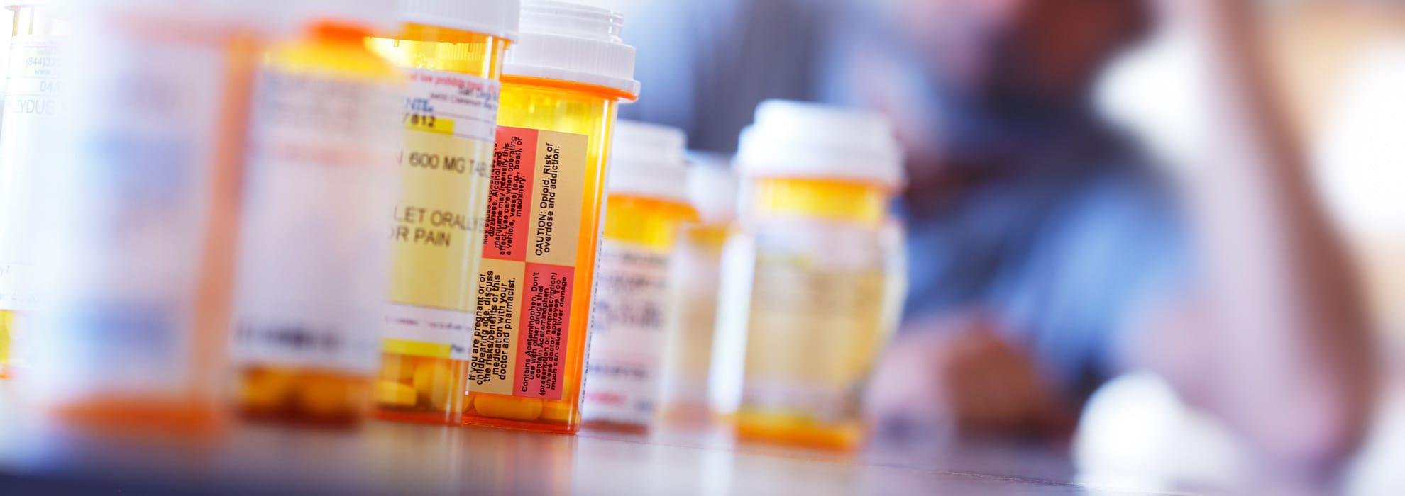 A row of medical pills with man looking at them from the background.