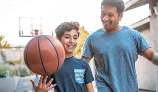 Father playing basketball with son.