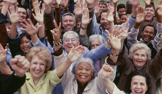 Crowd of people raising both hands to the sky.