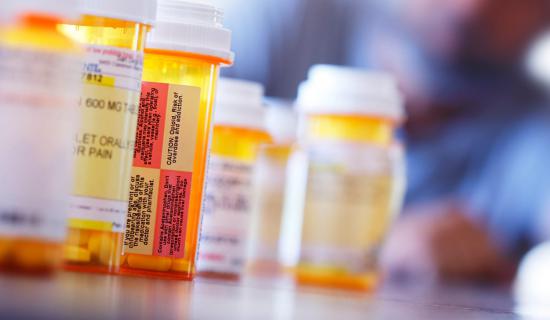 A row of medical pills with man looking at them from the background.