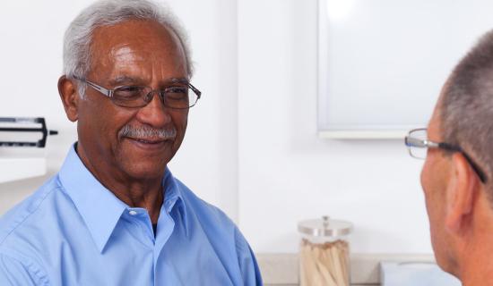 Man smiling and being helped by doctor.